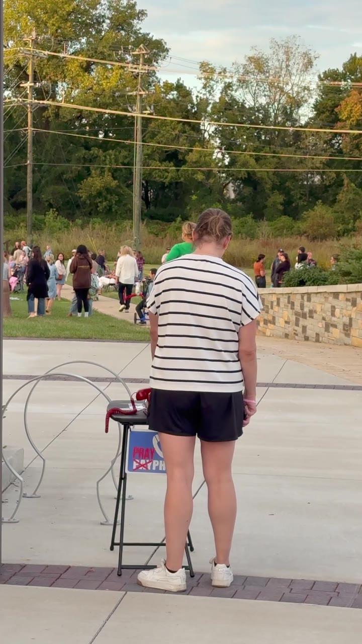 A woman praying at the PrayPhone table during an outdoor gathering